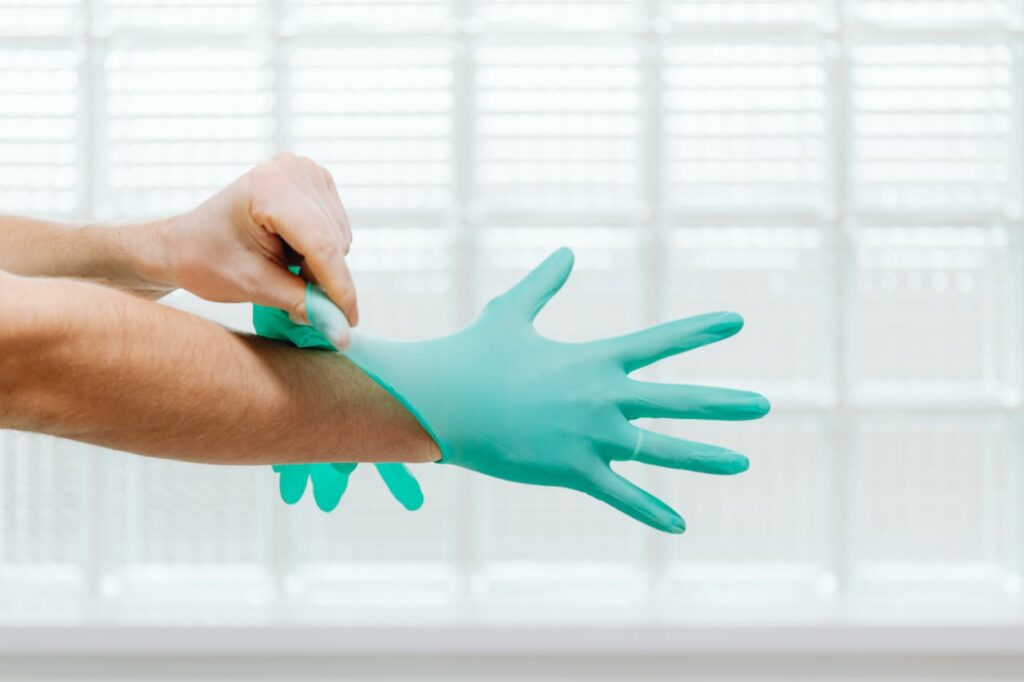 Close-up of hands putting on sterile gloves in a medical setting.